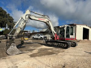 A red and white TB1140 excavator is parked in front of a building. - Viqan Replacement Tracks & Undercarriage Parts for Heavy Equipment