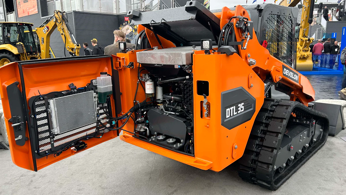 A Develon DTL35 track loader on display with its side panel open to reveal the engine and internal components. - Viqan Replacement Tracks & Undercarriage Parts for Heavy Equipment